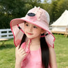 A young girl wearing a pink sun hat with a rabbit design outdoors.