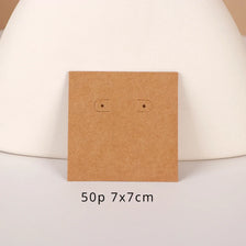 A square brown kraft card with two small cutouts is displayed on a white surface.