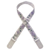A light purple woven guitar strap with green floral accents and leather accents, shown in an X shape.