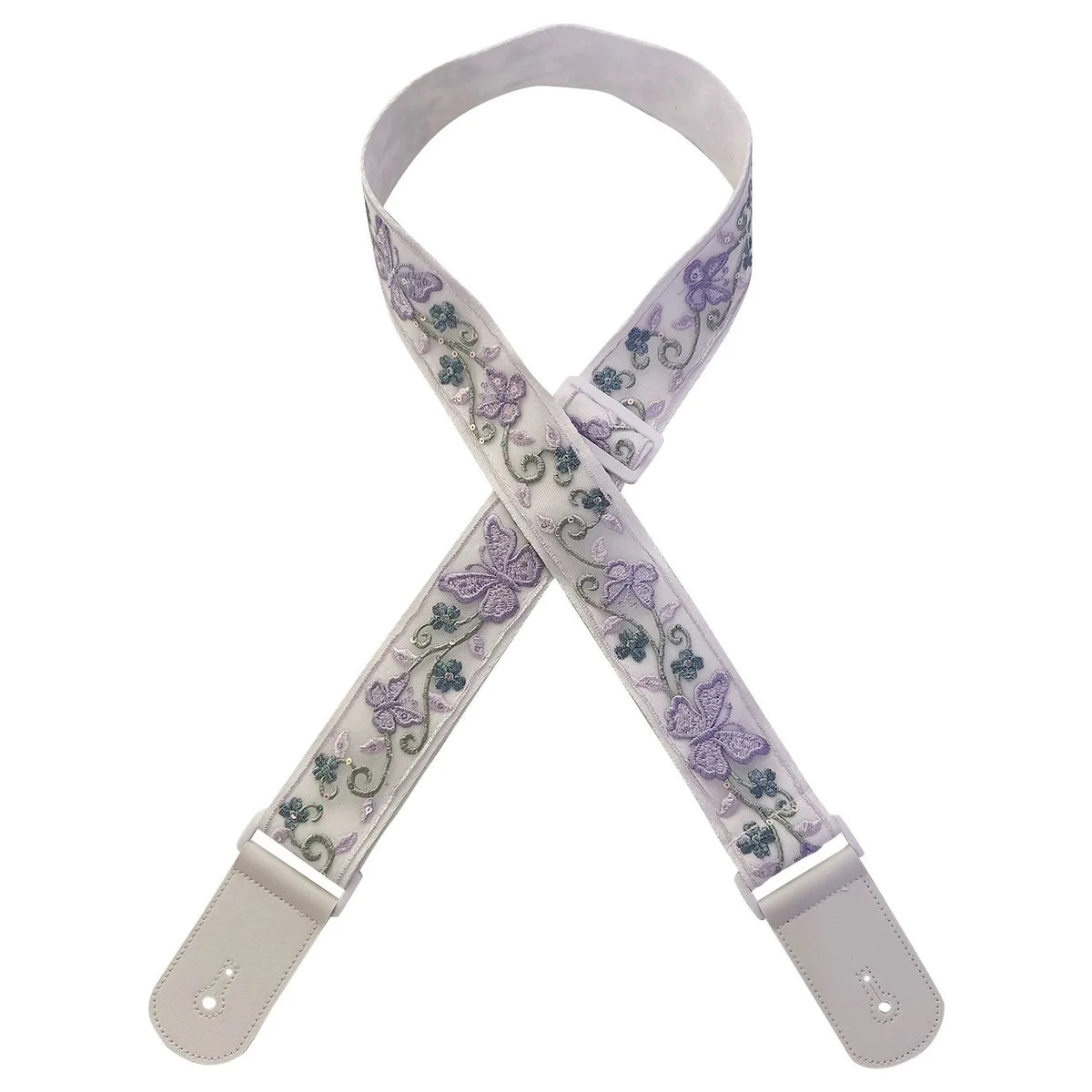 A light purple woven guitar strap with green floral accents and leather accents, shown in an X shape.