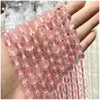 A hand holds a string of small, translucent pink and clear natural stone beads for DIY jewelry making.