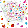 A collection of colorful acrylic gem stickers for face, nails, and crafts scattered on a white background.