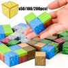 A hand holds colorful magnetic building cubes in various shades of green, blue, and brown.