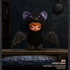 A black plush doll with purple ears and dark wings is displayed against a dark background.