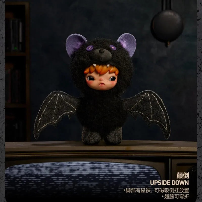 A black plush doll with purple ears and dark wings is displayed against a dark background.