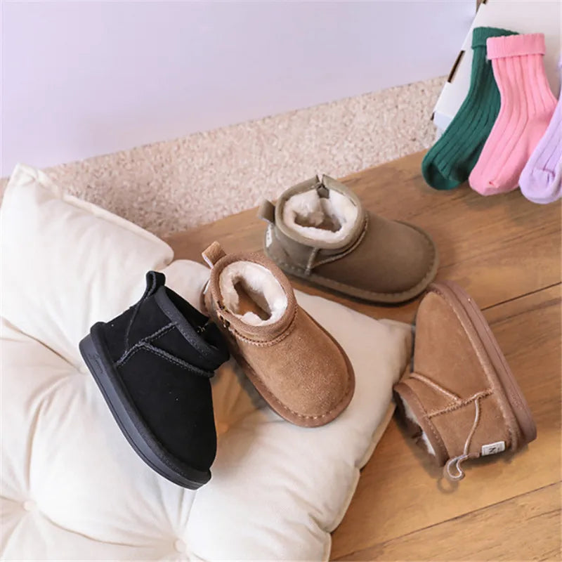 A collection of cozy winter snow boots for toddlers in various colors and materials resting on a wooden surface.