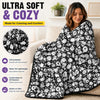 A woman is relaxing on a couch with a black and white patterned soft blanket for coloring and comfort.