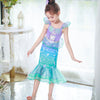 A young girl models a purple and teal mermaid fantasy dress with a ruffled fishtail skirt.