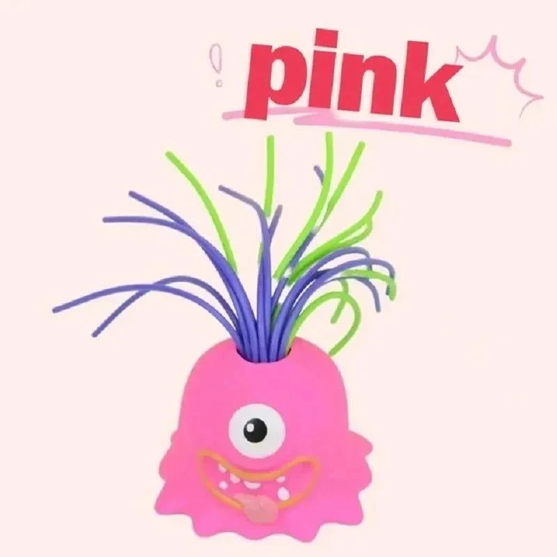 A pink, monster-shaped stress relief toy with a wide grin and purple hair.