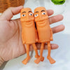 Two orange sensory decompression toys resembling stylized figures are held in a hand against a white background.