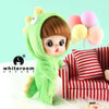 A small green plush doll with a hood and brown hair is shown next to a red and white striped sofa.