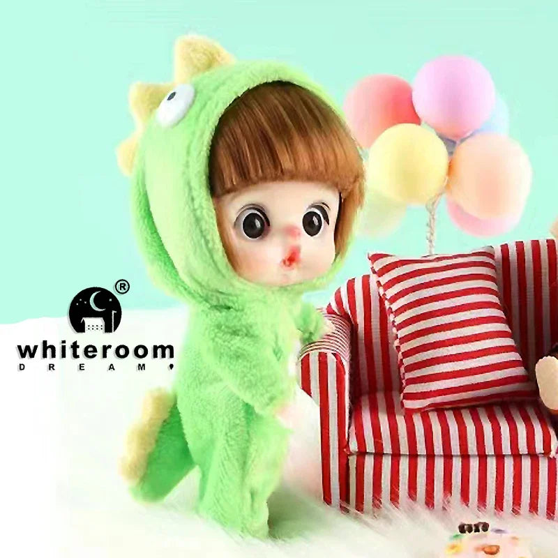 A small green plush doll with a hood and brown hair is shown next to a red and white striped sofa.