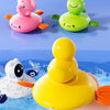 A hand is pulling a yellow frog water wheel bath toy through the water.