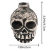 A weathered ceramic Aztec skull whistle with a detailed face and teeth, shown against a white background.