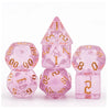 A set of seven translucent pink glitter polyhedral dice, including a tetrahedron and a cube.