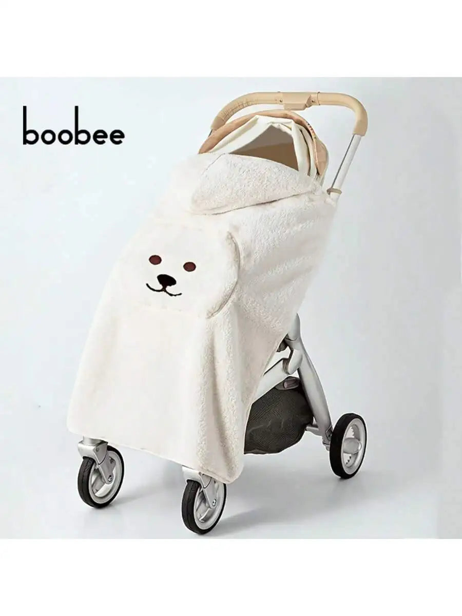 A beige baby windproof cape blanket with a dinosaur design is shown on a stroller.