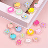 A collection of colorful enamel charm beads in various shapes and colors arranged on a white box.