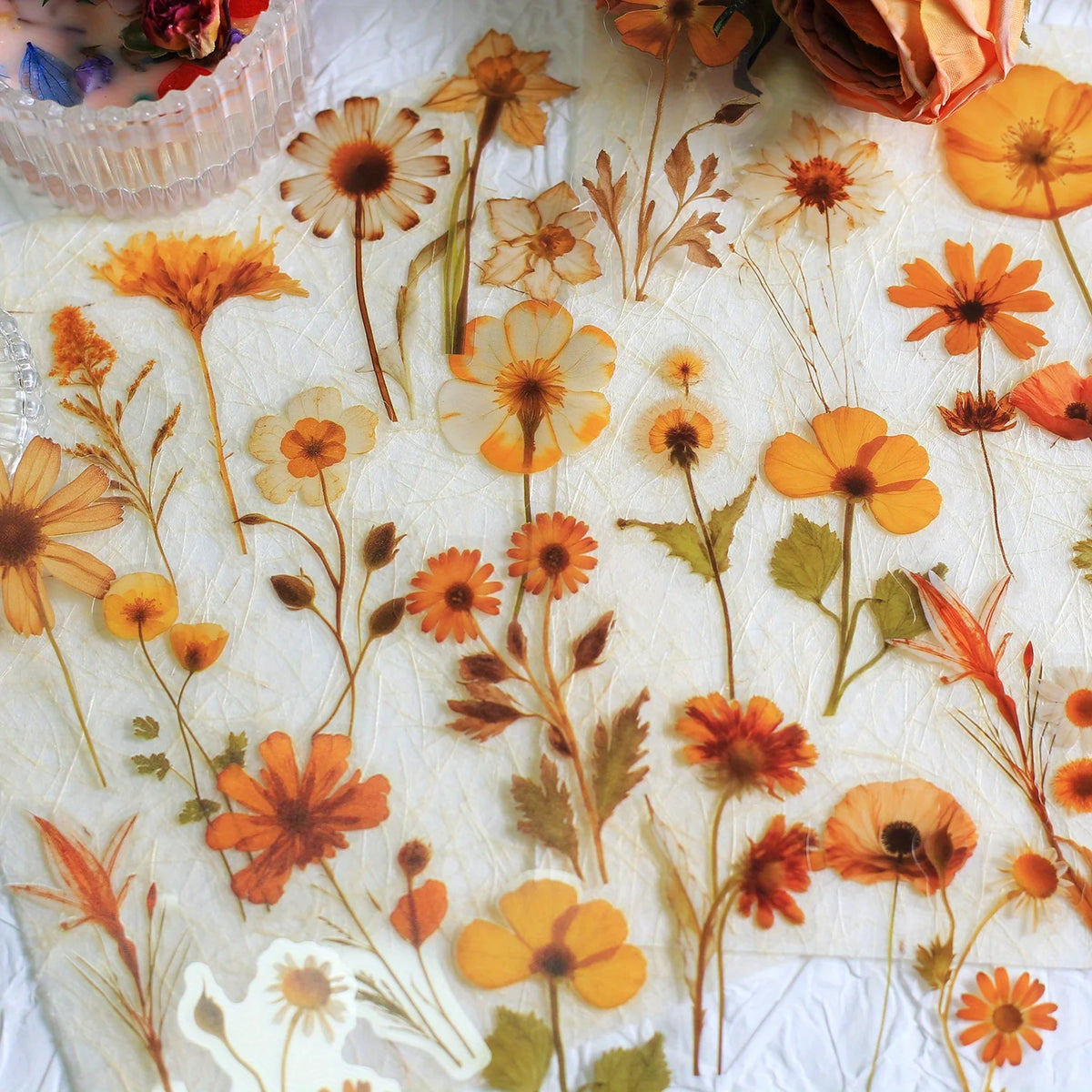 A sheet of transparent floral stickers featuring various orange, yellow, and brown flower designs for crafts.