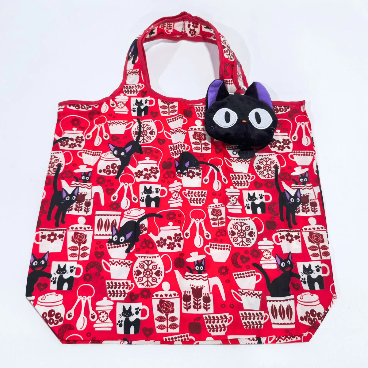 A red fabric tote bag featuring a pattern of black cats and various red decorative elements.