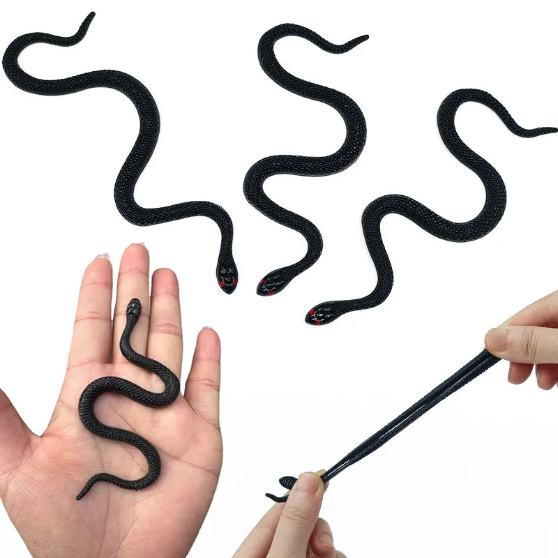 A hand is holding a realistic soft rubber black snake prop with a flexible body.