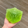 A hand holds a translucent lime green frosted matte jumbo stress ball against a neutral background.