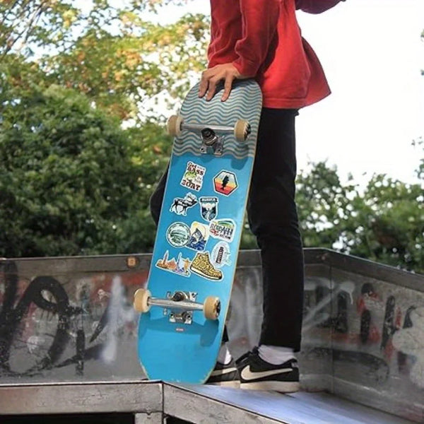 A person holds a blue surfboard decorated with fishing theme vinyl decals outdoors.
