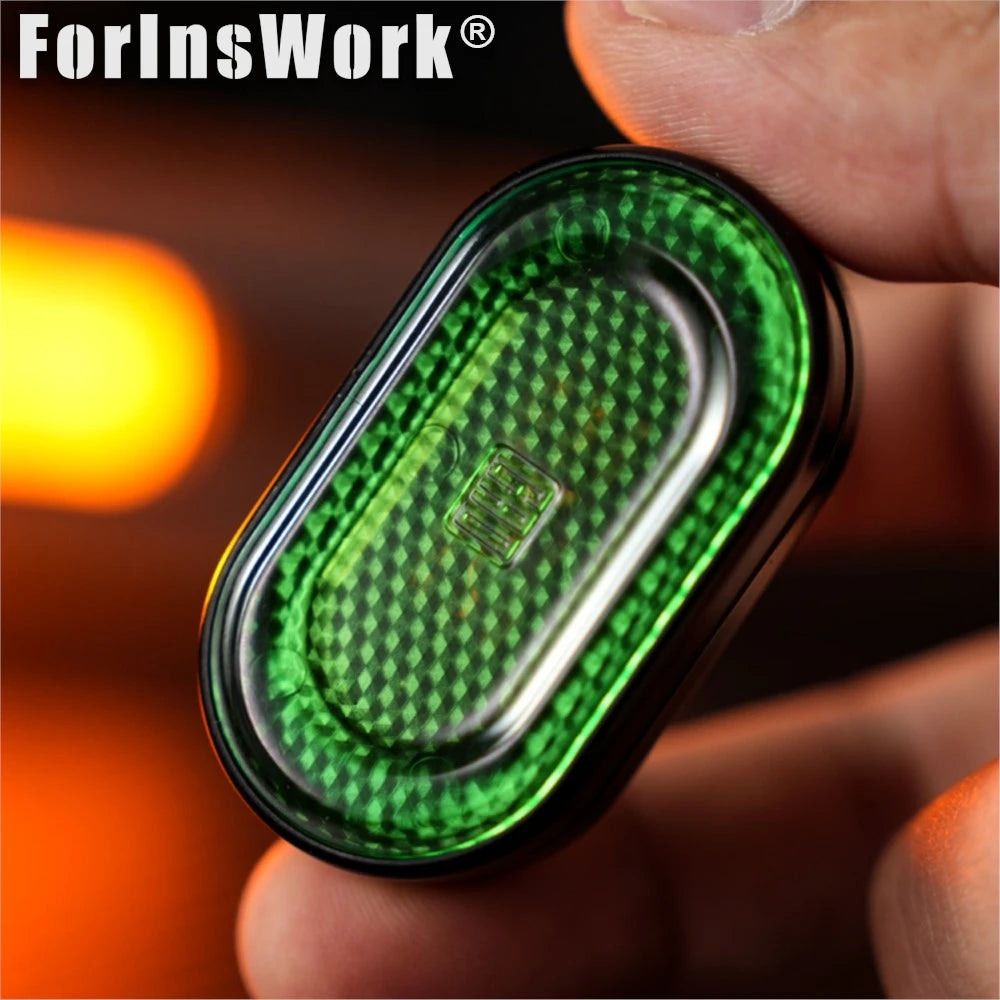 A hand holds a green metal mechanical fidget slider with a diamond gem design.