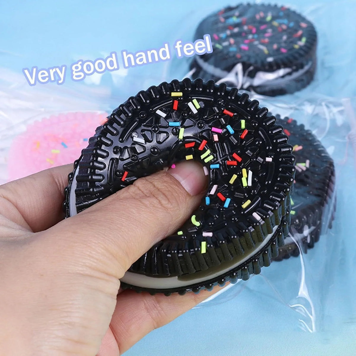 A hand holds a black squishy stress relief toy with colorful confetti sprinkles, demonstrating its good hand feel.