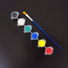 A set of twelve colored acrylic paint droppers and a brush arranged in a line on a dark surface.