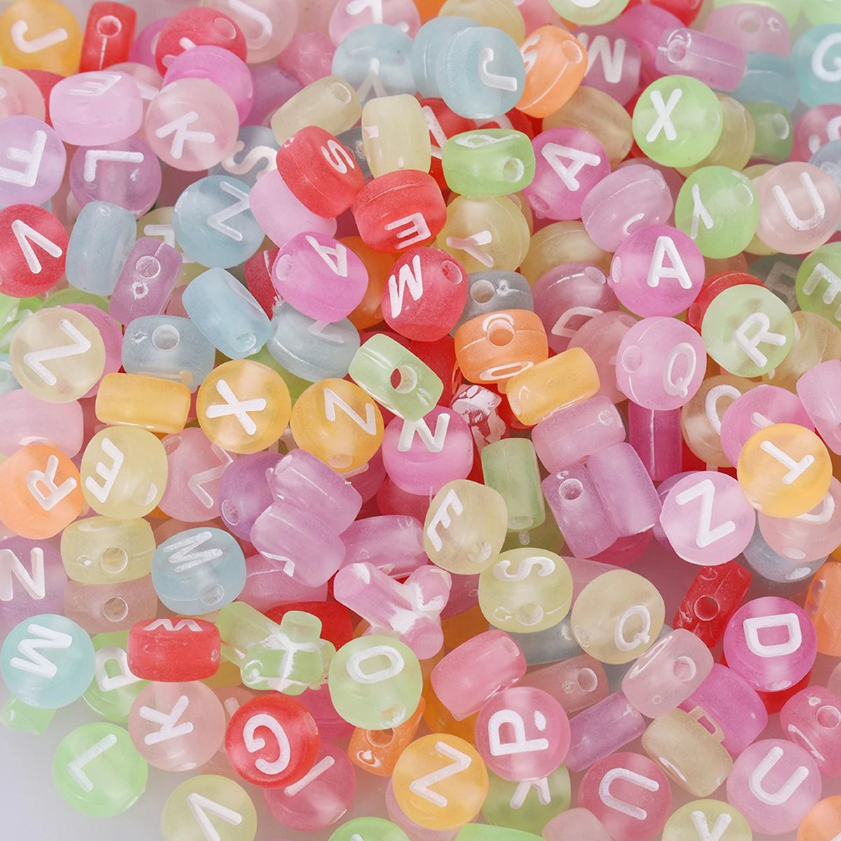 A close-up view of a large quantity of round acrylic alphabet beads in various pastel colors like pink, green, yellow, and bl