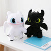 A white and black dragon plush toy sitting next to a blue book.