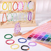 A display of various colored round glass beads for jewelry making, arranged in rows and scattered on a white surface.