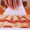 A hand places a white triangular tool onto a diamond painting surface.