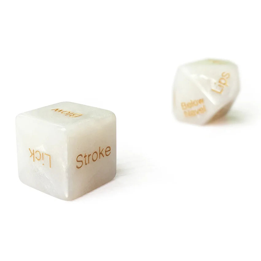 A white, translucent table game die with gold lettering showing the words Lick and Stroke.