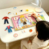 A child is interacting with an interactive learning busy book featuring cards for word recognition, shape matching, and logic