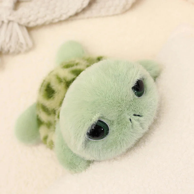 A soft, light green plush sea turtle stuffed animal with large eyes resting on a white surface.