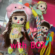 A pink-haired BJD doll with long brown hair and a yellow phone lanyard displayed in its box.