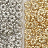 A close-up view of two strands of small spacer beads, one silver and one gold, used for jewelry making.