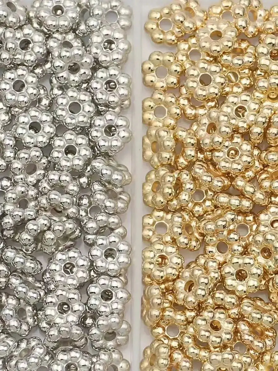 A close-up view of two strands of small spacer beads, one silver and one gold, used for jewelry making.