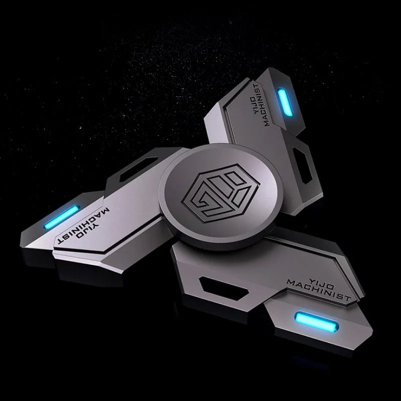 A silver metal fidget spinner with glowing blue accents and a central emblem, shown from an angled view.