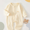 A cream-colored, ribbed soft cotton baby romper for newborns and infants lying on a light surface.