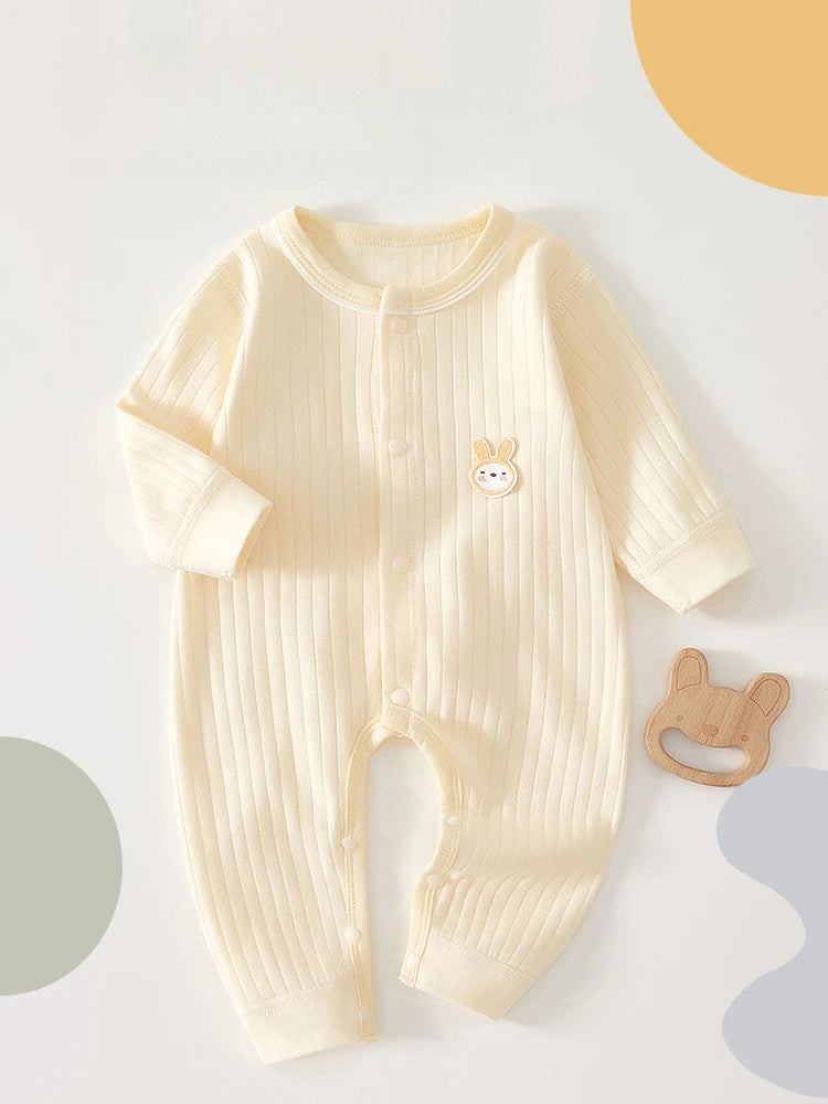 A cream-colored, ribbed soft cotton baby romper for newborns and infants lying on a light surface.