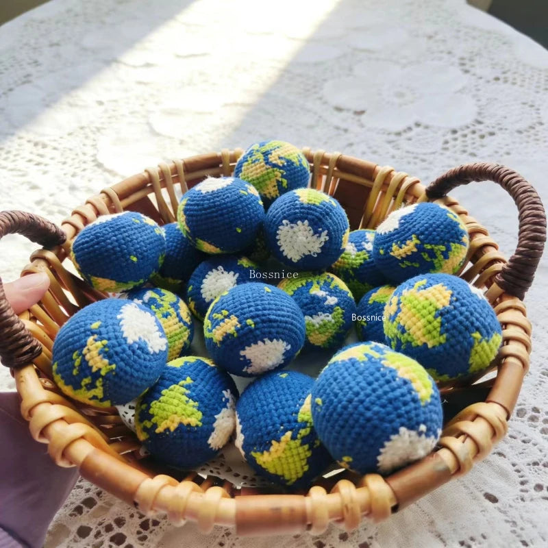 A woven basket filled with handcrafted crochet earth keychain charms in blue and green colors.