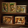 A wooden miniature dollhouse kit featuring detailed furniture, plants, and lighting elements displayed in an open box.