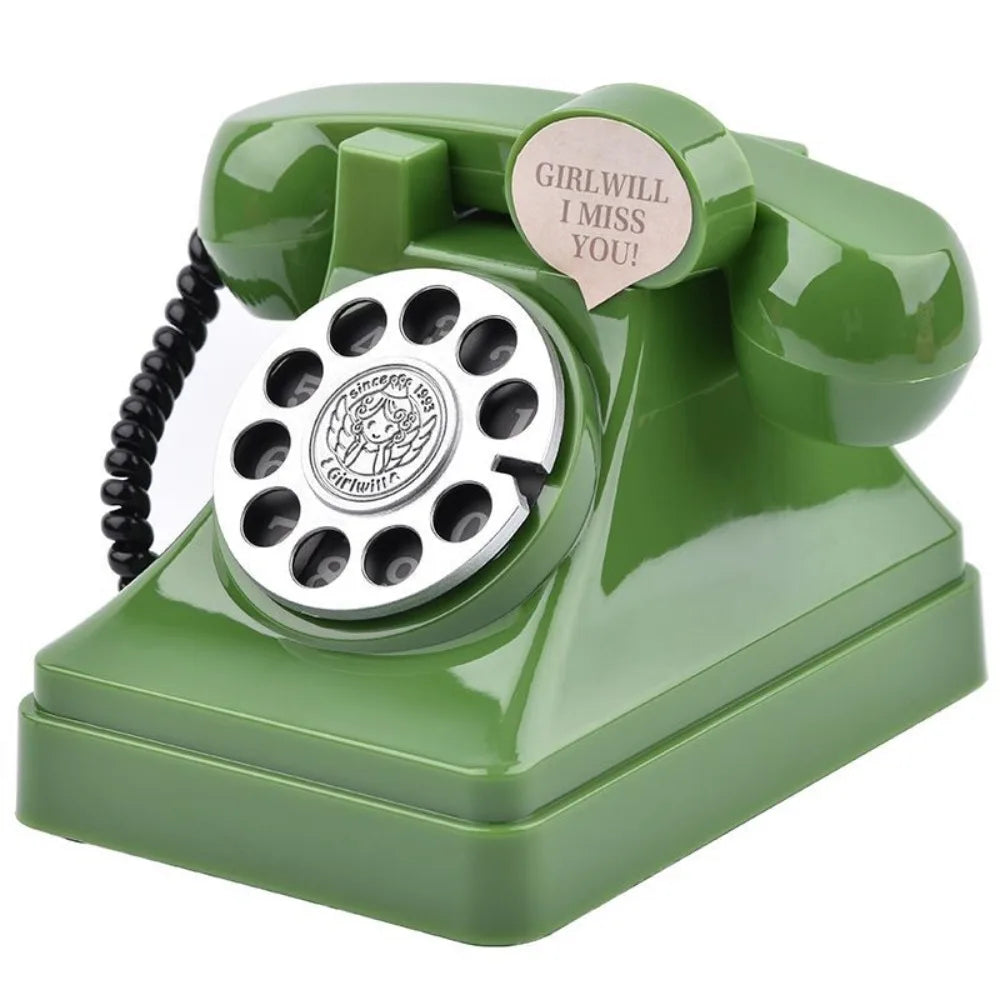 A vintage rotary telephone shaped like a piggy bank in olive green with a heart-shaped cutout that says I miss you