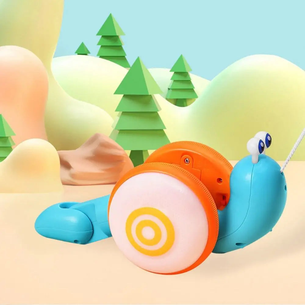 An orange and light blue musical pull-along snail toy is shown on a light surface with green trees in the background.