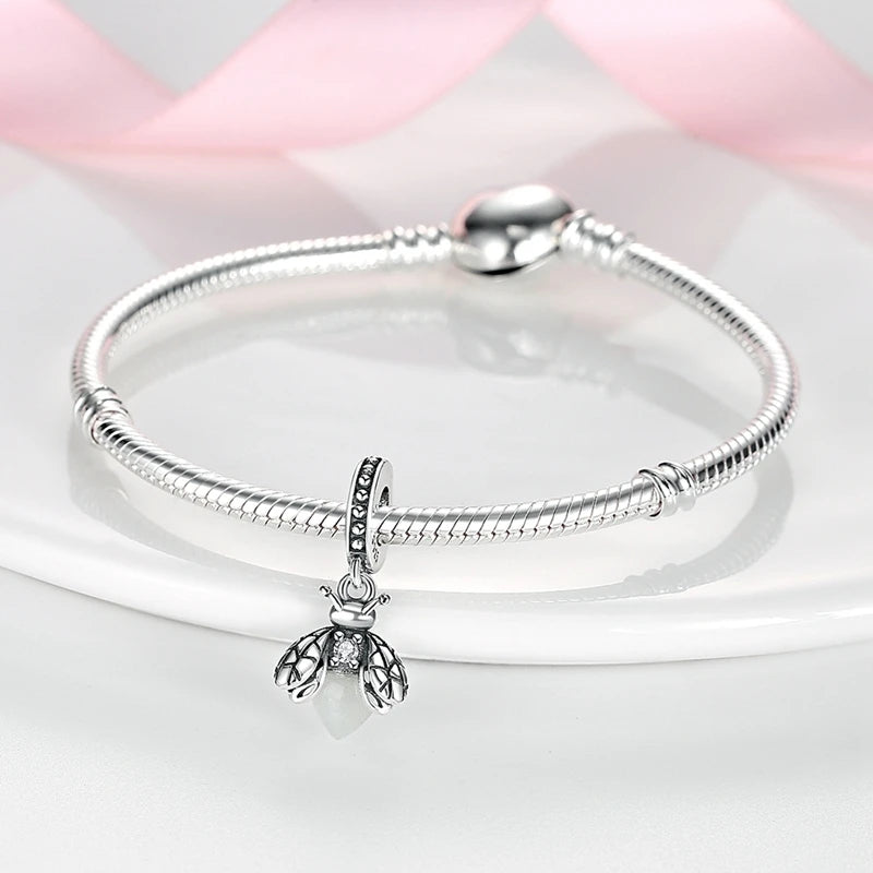 A sterling silver bracelet with a charm bead is displayed on a white surface.
