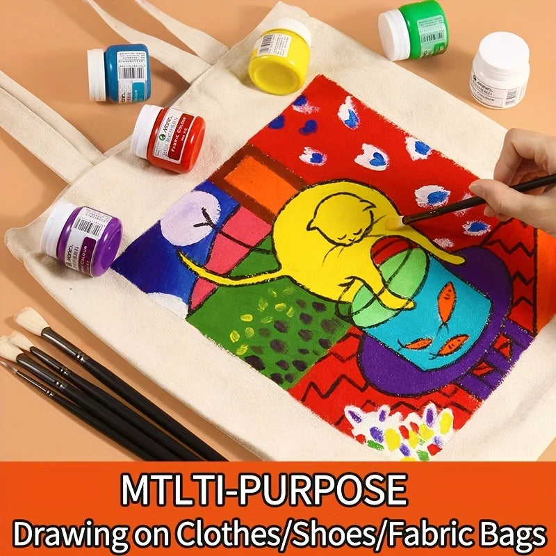 A set of permanent fabric paint and brushes displayed on a beige fabric bag with colorful artwork.