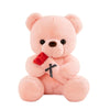 A soft pink plush bear with embroidered features and holding a red ribbon.
