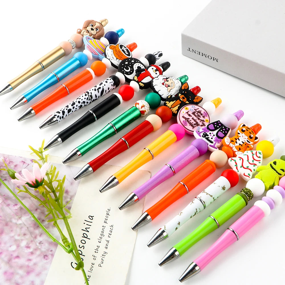 A collection of colorful beadable ballpoint pens with various tips and designs arranged on a white background.